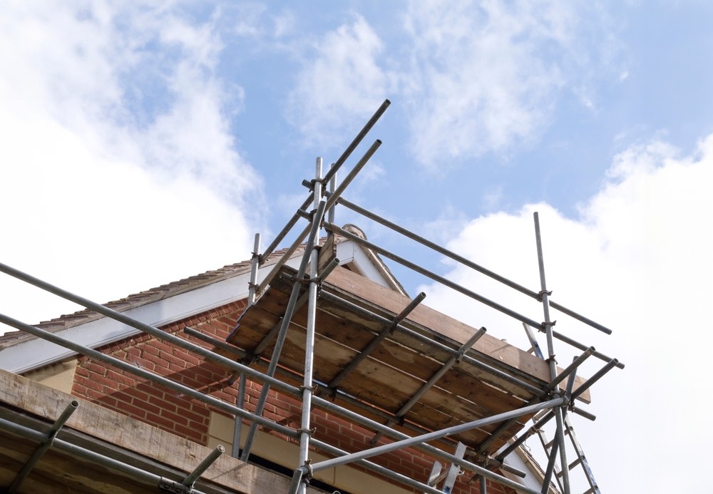 Scaffolding to the gable end and roof edge of a brick house